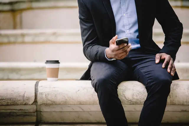 man sitting with a to-go cup next to him