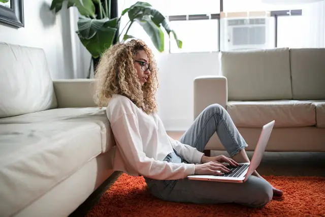 female sitting on the floor using a laptop