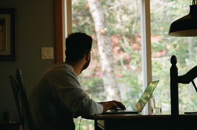 man in front of a laptop looking out the window