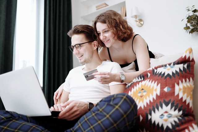 Happy couple with credit card in front of a laptop