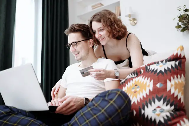Credit Card Rewards Definition: Pros and Cons 1 Happy couple with credit card in front of a laptop