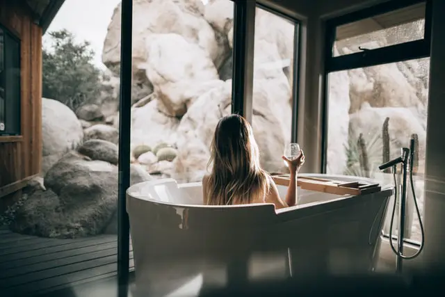 Woman in a bathtub holding glass of wine