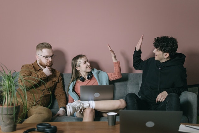 three friends on a couch doing hi-fives