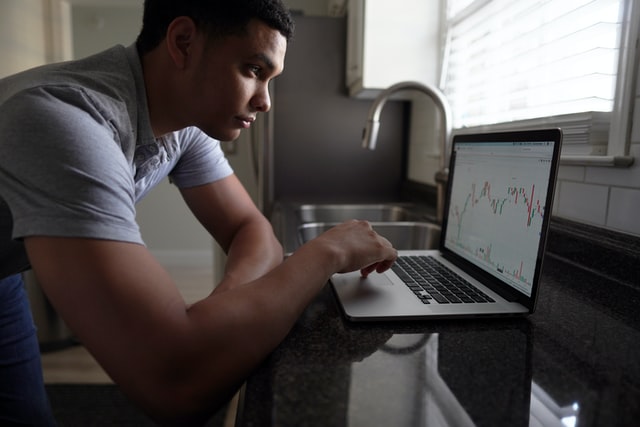 young man looking at a trading chart on a laptop