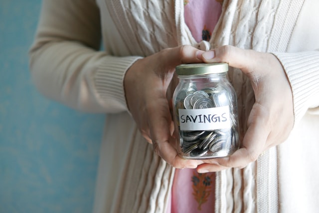 Person holding a savings jar with coins