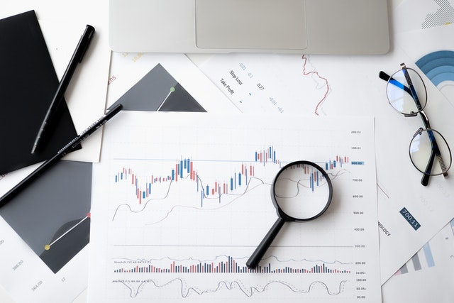 stock trading chart on paper, glasses and magnifying glass on top