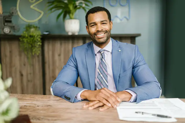 smiling man in suit at a dest