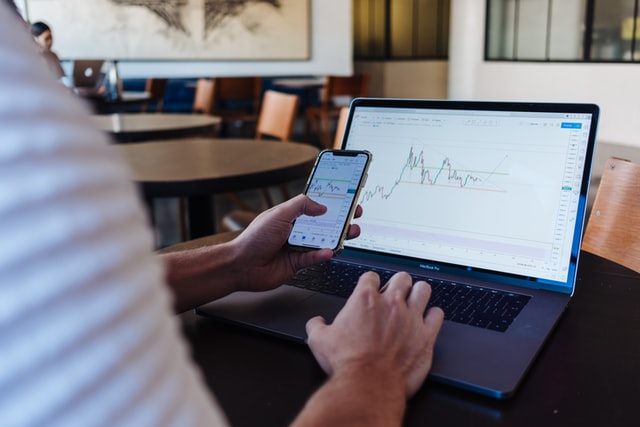 person infront of a laptop holding a phone