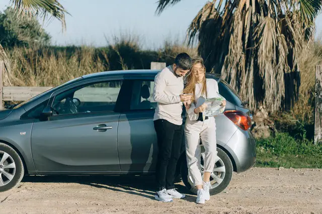 Couple standing next to a car