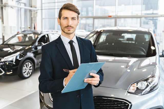 Man in suit in front of a car