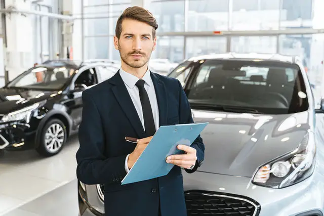 Should The Newly Engaged Own One Car Or Two When First Starting Out 2 Man in suit in front of a car
