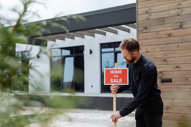 man placing a home for sale sign