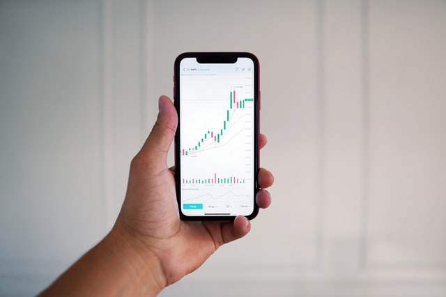 Pattern Trading Strategy: Beginners Guide 3 hand holding a cellphone with trading chart on it