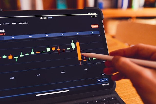 hand pointing at trading chart on a monitor