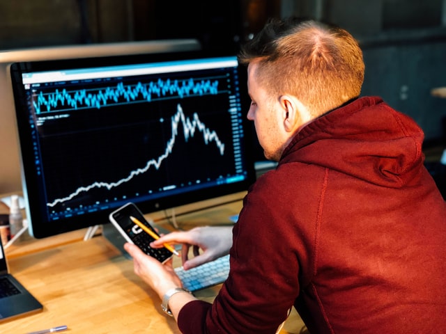man in front of a monitor with trading chart
