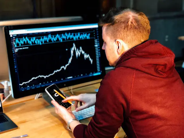 man in front of a monitor with trading chart