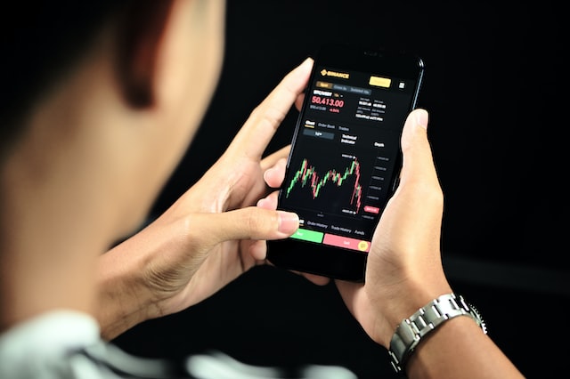 Profiting from Market Momentum with Trend Trading 1 man on his phone looking at trading chart