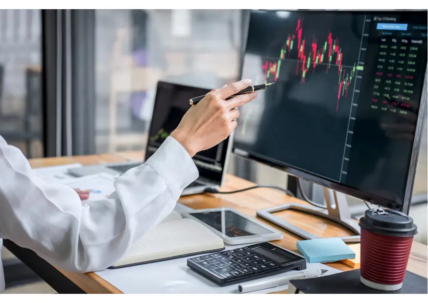 Hand pointing at a trading chart on a monitor