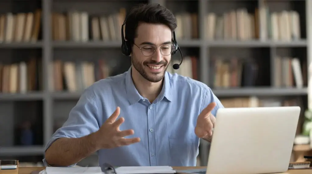 Online tutor wearing a headset, actively explaining concepts via laptop video call.
